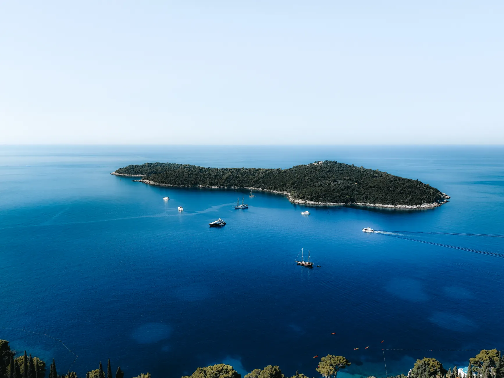 Stunning aerial view of an island in Dubrovnik, Croatia surrounded by turquoise waters and boats.